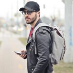 A fashionable young man in Budapest checking his smartphone on a busy street.